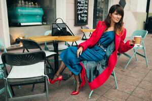 stylish woman in red coat sitting in cafe photo