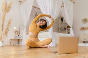 joven bonito mujer haciendo yoga a hogar foto