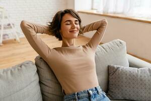 pretty young woman realxing at home sitting on sofa, smiling, happy, free time photo