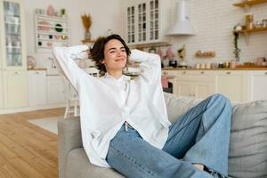 pretty young woman realxing at home sitting on sofa, smiling, happy, free time photo