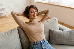 pretty young woman realxing at home sitting on sofa, smiling, happy, free time photo