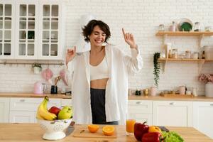 joven bonito mujer Cocinando a hogar, Mañana cocina, sano comida foto