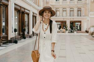 attractive woman walking in shopping street in Italy on vacation dressed in white summer fashion dress photo