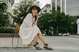 beautiful woman walking in street on vacation dressed in white summer fashion dress photo