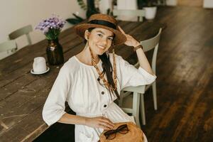 beautiful woman sitting in cafe on vacation dressed in white summer fashion dress photo