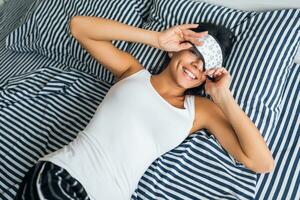 pretty sexy woman lying in bed in morning, wake up early, sleeping in mask photo
