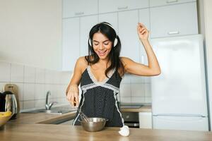 attractive smiling woman in pajamas having breakfast in kitchen photo