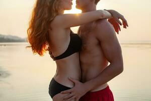 young sexy romantic couple in love happy on summer beach together having fun wearing swim suits photo