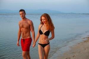 young romantic couple in love happy on summer beach together having fun wearing swim suits photo