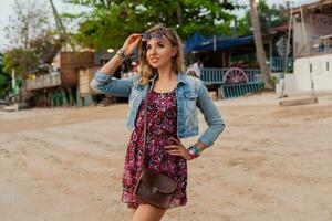 stylish woman in summer dress vacation walking on beach with sunglasses photo