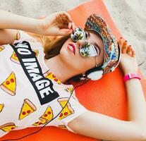 attractive hipster woman sitting on beach listening to music on headphones photo
