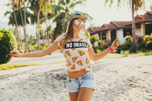 atractivo hipster mujer sentado en playa escuchando a música en auriculares foto