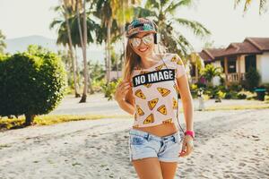 attractive hipster woman sitting on beach listening to music on headphones photo