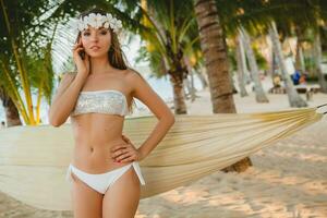 young sexy woman in white bikini swimsuit on tropical beach photo