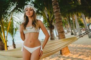 young sexy woman in white bikini swimsuit on tropical beach photo