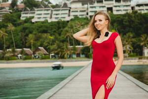 young beautiful attractive woman standing alone on pier red long dress photo