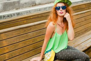 joven elegante hipster jengibre mujer, sentado en banco foto