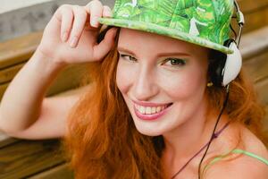 young stylish hipster ginger woman, sitting on bench, listening music photo