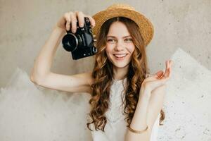 young pretty smiling happy woman in straw hat holding vintage photo camera