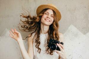 young pretty woman in summer vacation style outfit holding vintage photo camera