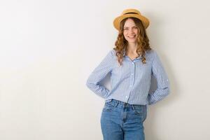 young beautiful stylish woman in summer style outfit posing on white wall wearing straw hat photo