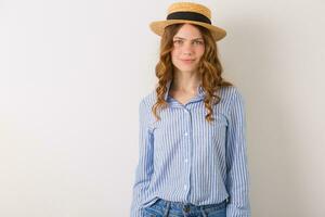 young beautiful stylish woman in summer style outfit posing on white wall wearing straw hat photo