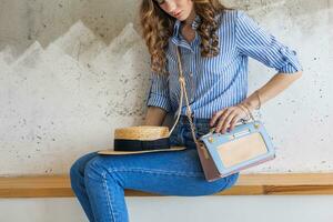 young attractive stylish woman sitting at wall background, straw hat photo