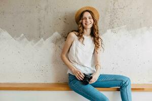 young pretty woman in summer vacation style outfit holding vintage photo camera