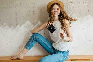 young pretty woman in summer vacation style outfit holding vintage photo camera