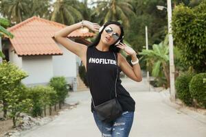 young stylish hipster woman in black t-shirt, jeans, listening to music on headphones photo