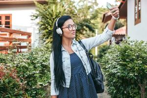 young stylish woman walking with smartphone, listening to music on headphones photo