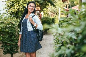 young stylish woman walking with smartphone, listening to music on headphones photo