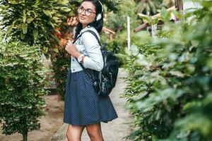 young stylish woman walking with smartphone, listening to music on headphones photo