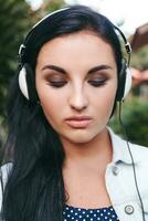 joven elegante mujer caminando, escuchando a música en auriculares foto