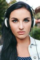 joven elegante mujer caminando, escuchando a música en auriculares foto