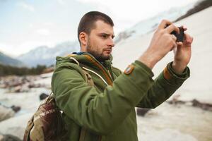 young hipster man hiking in mountains, winter vacation photo