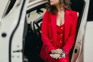 beautiful sexy rich business woman in red suit posing in white car photo