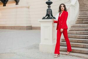 beautiful sexy rich business woman in red suit walking in city street, spring summer fashion trend photo