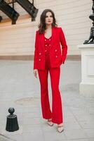 beautiful sexy rich business woman in red suit walking in city street, spring summer fashion trend photo