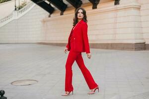 beautiful sexy rich business woman in red suit walking in city street, spring summer fashion trend photo