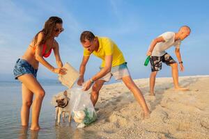 young people friends picking up trash and garbage on tropical beach photo