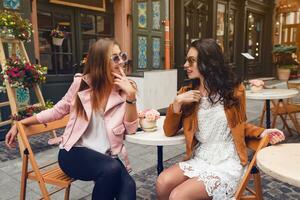 dos joven elegante mujer sentado a café foto