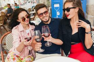 young hipster company of friends sitting in city street cafe photo