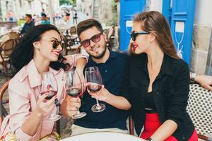 young hipster company of friends sitting in city street cafe photo