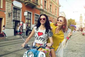 two young beautiful hipster women riding on motorbike city street photo