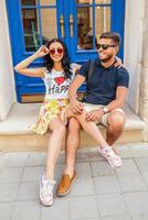 young beautiful hipster couple in love sitting on old city street photo