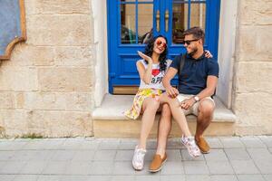 young beautiful hipster couple in love sitting on old city street photo