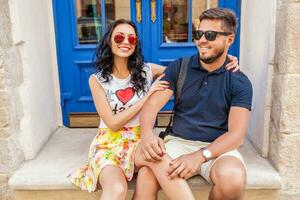 young beautiful hipster couple in love sitting on old city street photo