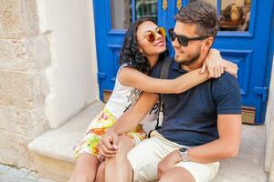 young beautiful hipster couple in love sitting on old city street photo