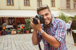 young man photographer taking pictures, holding digital photo camera